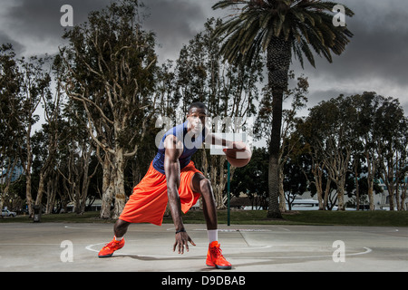 Jeune homme jouant au basket-ball sur cour, portrait Banque D'Images