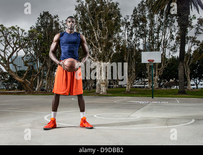 Jeune homme jouant au basket-ball sur cour, portrait Banque D'Images