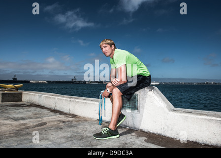 Jeune homme dans le sportswear resting on pier Banque D'Images