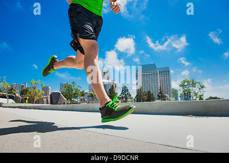 Jeune homme jogging en ville, low section Banque D'Images