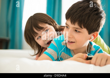 Girl boy listening to mp3 player on bed Banque D'Images