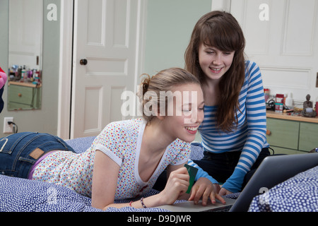 Girls lying on bed with laptop internet shopping Banque D'Images