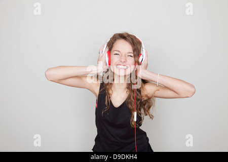 Jeune fille portant des écouteurs avec les mains sur les oreilles Banque D'Images