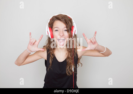 Girl wearing headphones faisant des signes diable et sticking tongue out Banque D'Images