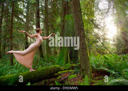 Mature Woman standing on log in forest Banque D'Images