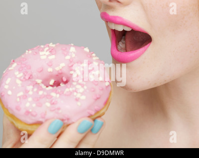 Rouge à lèvres Rose woman eating donut Banque D'Images