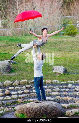 Mid adult dancers performing avec parapluies rouges dans Stone Circle Banque D'Images