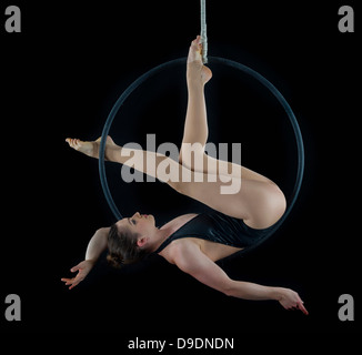 Aerialist performing on hoop en face de fond noir Banque D'Images