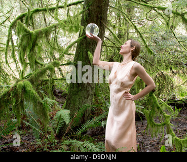 Femme mature à la boule de cristal en forêt en Banque D'Images