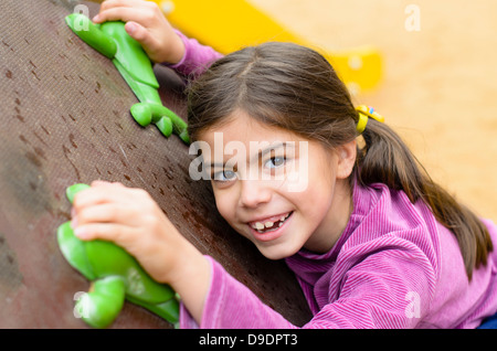 Petite fille sur un mur d'escalade dans un parc Banque D'Images