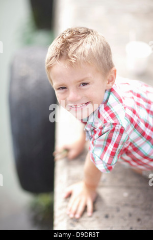 Portrait of young boy leaning on pier wall Banque D'Images