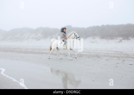 Woman riding horse on beach Banque D'Images