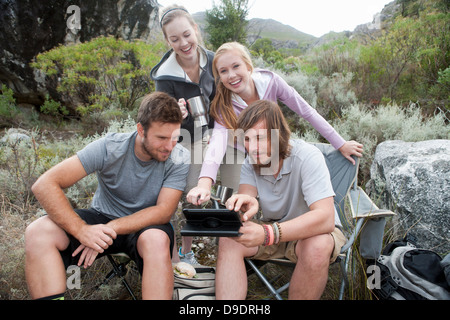 Groupe de jeunes randonneurs à la recherche à l'ordinateur lors d'une pause Banque D'Images