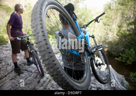 Jeune couple avec des vélos de montagne sur rock Banque D'Images