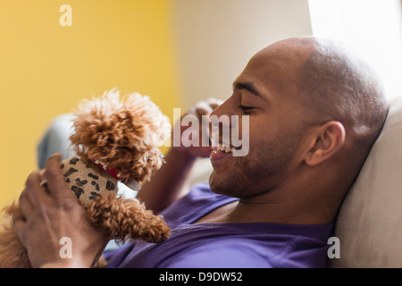 Mid adult male relaxing on sofa with dog Banque D'Images