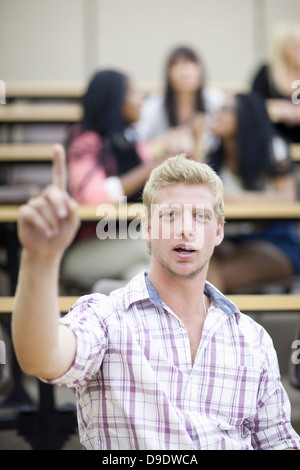 Male student in lecture avec bras levé