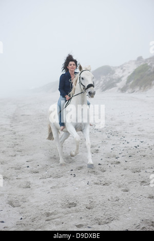 Woman riding horse on beach Banque D'Images