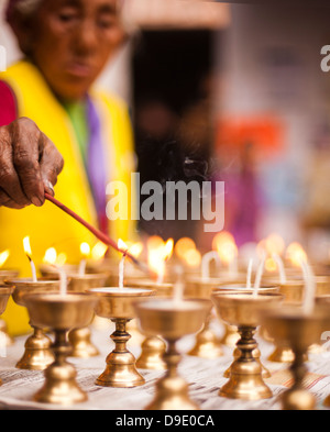 Éclairage femme bougie dans un monastère, monastère tibétain, Delhi, Inde Banque D'Images