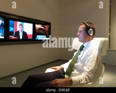 L'homme d'affaires dans un salon privé, de l'aéroport, à regarder les nouvelles, télévision Banque D'Images