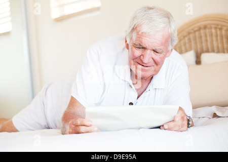 Man lying on bed and reading newspaper Banque D'Images