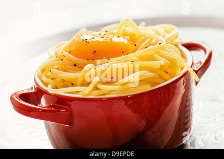 Spaghetti avec yolke d'oeufs dans un petit bol rouge Banque D'Images