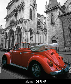 Un orange vif, open top VW Coccinelle, voiture avec le haut vers le bas, stationné près de l'Eglise Notre Dame, Dijon, Bourgogne, France. Image avec coloration sélective. Banque D'Images