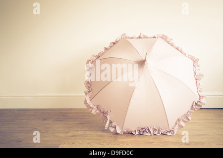 Un parapluie à froufrous rose placé sur un sol en bois Banque D'Images