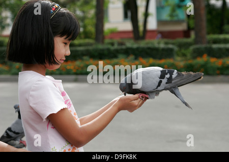 Fille Kazakh pigeon d'alimentation dans le parc (Parc Panfilov), Almaty, Kazakhstan, en Asie centrale Banque D'Images