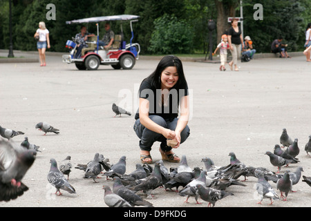 Alimentation fille pigeons dans le parc (Parc Panfilov), Almaty, Kazakhstan, en Asie centrale Banque D'Images