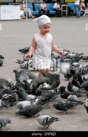 Petite fille nourrir les pigeons dans le parc (Parc Panfilov), Almaty, Kazakhstan, en Asie centrale Banque D'Images