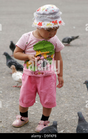 L'alimentation de l'enfant les pigeons dans le parc (Parc Panfilov), Almaty, Kazakhstan, en Asie centrale Banque D'Images