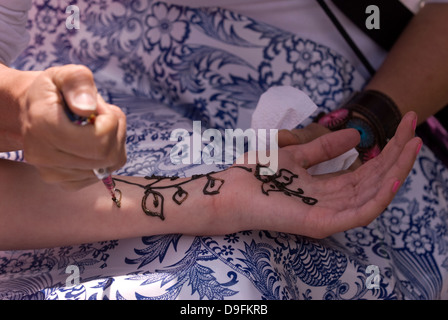 Jeune fille ayant ses bras peint avec le henné, Petersfield, Hampshire, Royaume-Uni. Banque D'Images