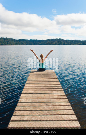 Femme assise sur une jetée, lac Ianthe, West Coast, South Island, New Zealand Banque D'Images