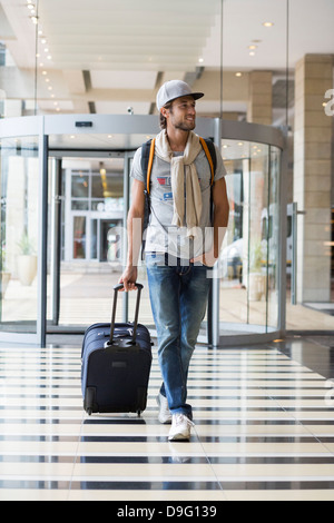 L'homme tirant ses bagages dans un aéroport Banque D'Images