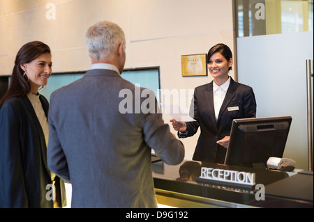 Business couple checking into hotel Banque D'Images