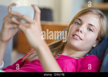 Portrait d'une fille à l'aide d'un téléphone mobile et smiling Banque D'Images