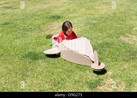 Fille jouant avec une pelouse en avion en carton Banque D'Images