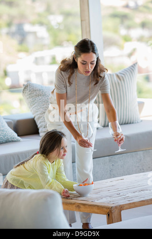 Woman putting stem verres sur une table à côté de sa fille à la maison Banque D'Images