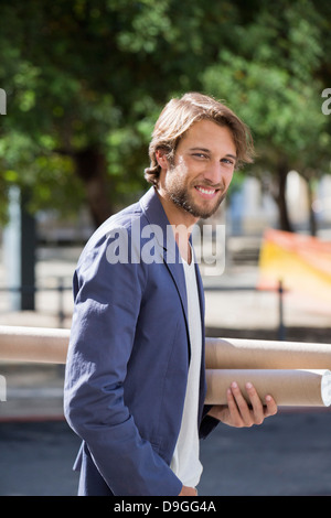 Portrait d'un architecte exerçant son activité sous les rouleaux de papier et souriant Banque D'Images