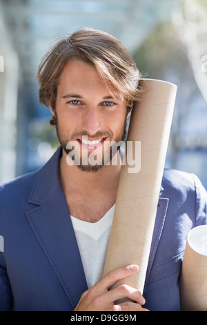 Portrait d'un architecte tenant un rouleau de papier et souriant Banque D'Images