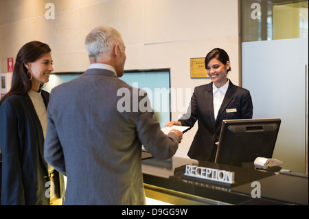 Business couple checking into hotel Banque D'Images