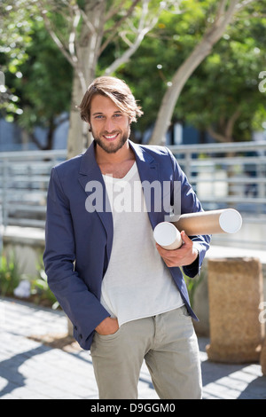 Portrait d'un architecte exerçant son activité sous les rouleaux de papier et souriant Banque D'Images