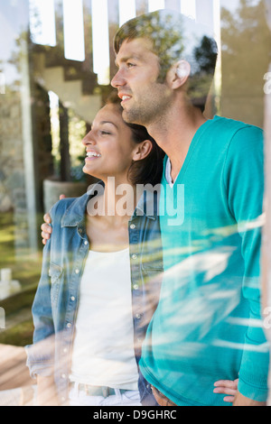 Smiling couple debout derrière un mur de verre Banque D'Images