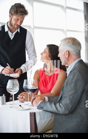 Garçon qui prend les commandes d'un couple dans un restaurant. Banque D'Images