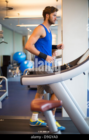 Homme qui court sur un tapis roulant dans une salle de sport Banque D'Images