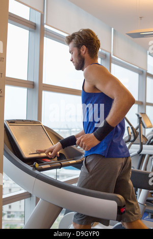 Homme qui court sur un tapis roulant dans une salle de sport Banque D'Images