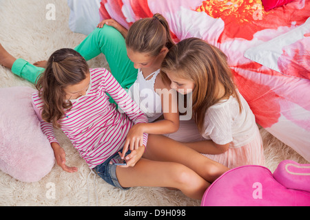 Trois jeunes filles à l'aide d'un téléphone mobile à un pyjama Banque D'Images