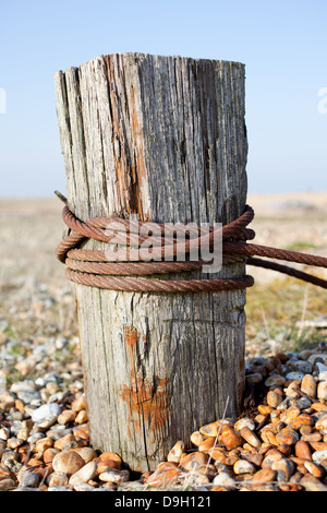 Ancien câble rouillé enroulée autour d'un post en bois. Banque D'Images