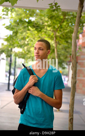 Un jeune homme marche sur un campus universitaire. Banque D'Images