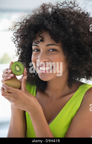 Portrait of a smiling woman showing kiwi fruits Banque D'Images